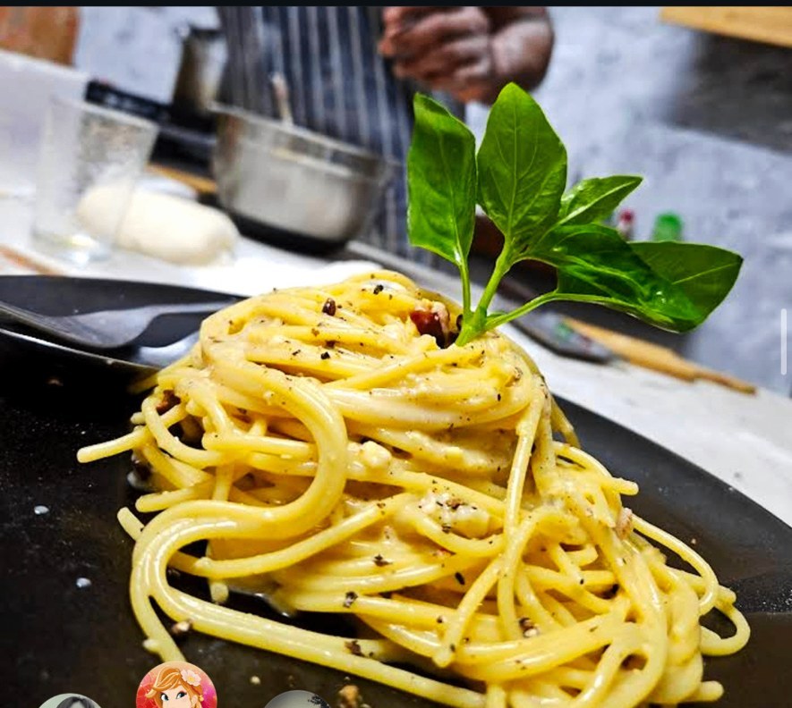Spaghetti cacio e pepe finished with fresh basil