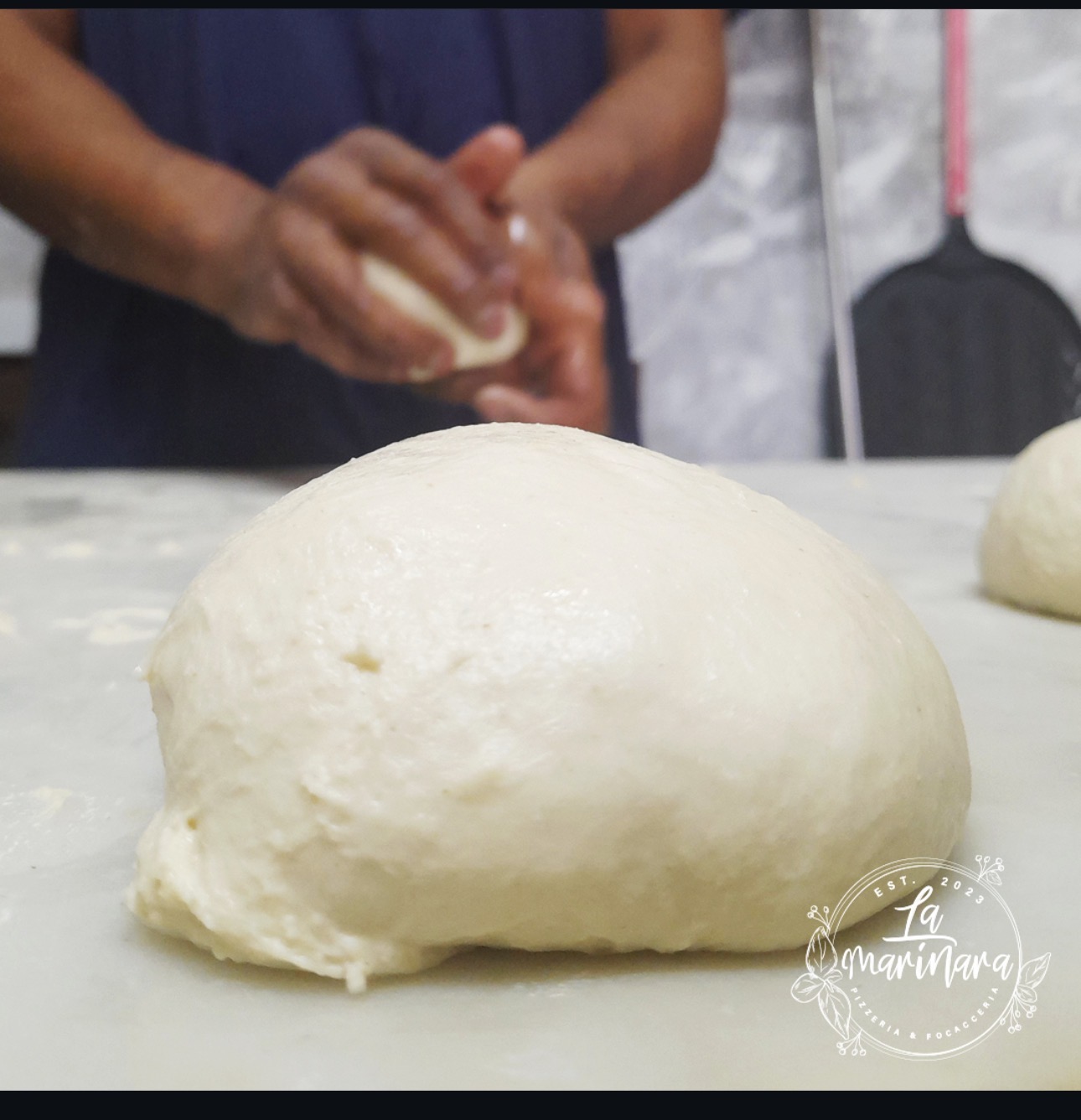 A ball of dough resting on the marble bench while Chef Paolo shapes the next one