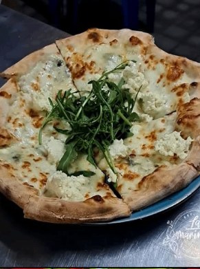 White pizza topped with a nest of wild rocket