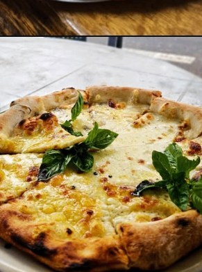 Cheese pizza with basil leaves on a wooden board